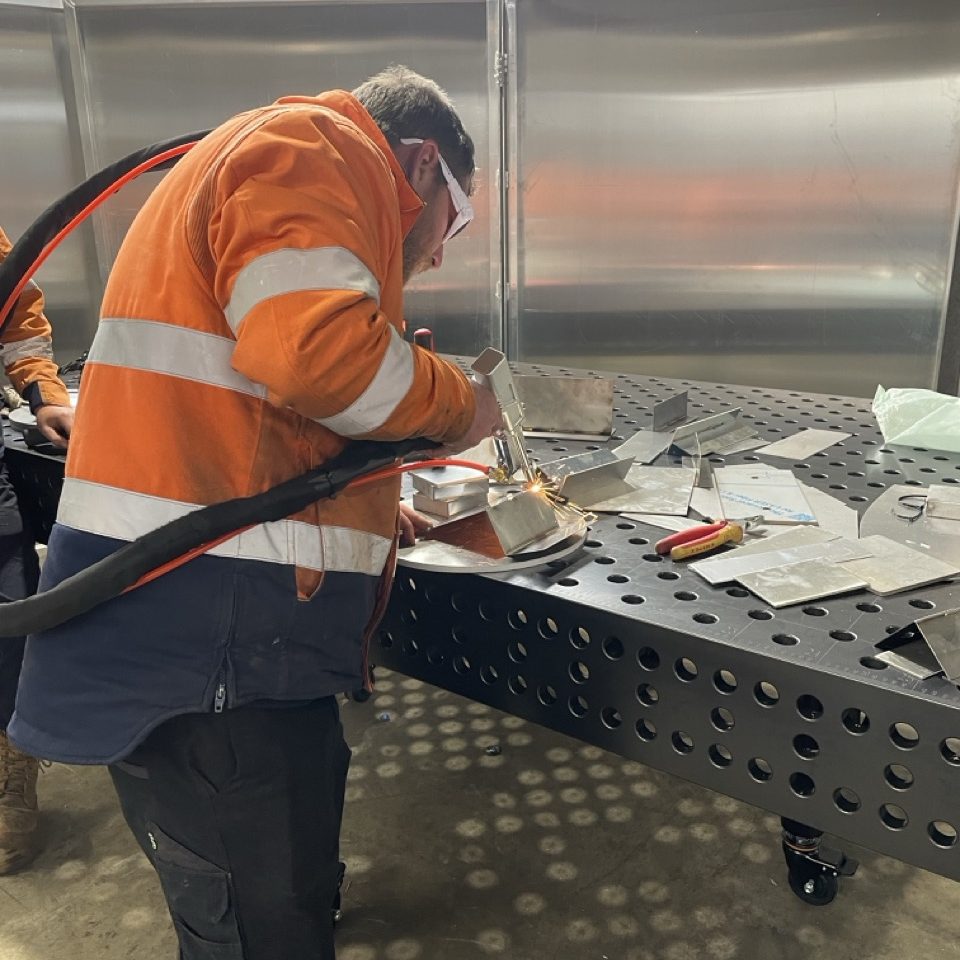 Metal fabricator welding on a workbench